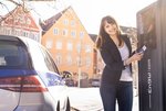 Eine Frau hält Ladekarte an eine Ladestation im öffentlichen Raum